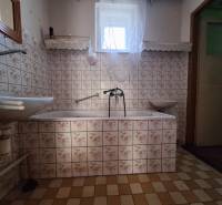 Fürdőszoba egy családi házban virágmintás csempékkel és káddal.