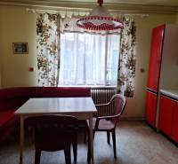 Konyha egy családi házban, piros bútorokkal, színes függönyökkel és műanyag székekkel.