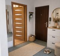 3 szobás lakás meleg világítással, faajtókkal és fehér bútorokkal.