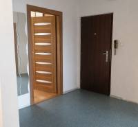 Előszoba egy háromszobás lakásban fa dekoros ajtókkal és tükörrel.