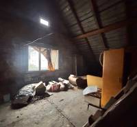 Tetőtéri szoba ablakokkal egy családi házban, tele régi tárgyakkal és bútorokkal.