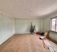 Szoba egy családi házban kék tapétával, karácsonyfa, ablak és tárolt tárgyak.