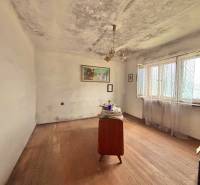 Szoba egy családi házban egyszerű bútorokkal és fa dekoros padlóval.