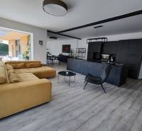 Nappali egy családi házban, fa mintázatú padlóval és kényelmes kanapéval.