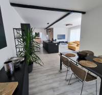 Ebédlő és nappali kanapéval, asztallal és fa dekorációjú padlóval a családi házban.