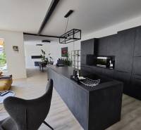 Nappali összekötve a konyhával egy családi házban, fa mintázatú padlóval.