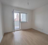 Szoba egy kétszobás lakásban, fa dekorációjú padlóval és erkéllyel.