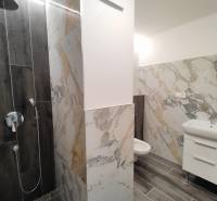 Fürdőszoba egy kétszobás lakásban márvány burkolattal és fa dekorációjú padlóval.