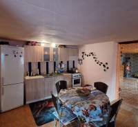 Családi ház konyhája étkezőasztallal, konyhapulttal és hűtőszekrénnyel.