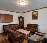 Nappali családi házban bőr ülőgarnitúrákkal és fa mintázatú padlóval.