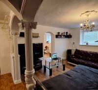 Nappali egy családi házban kanapéval, üvegasztallal és oszlopokkal.