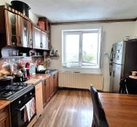 Családi ház konyhája konyhabútorral, háztartási gépekkel és fa dekorációjú padlóval.