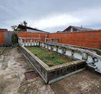 A Zacharovce-i családi ház udvara virágágyással és beton járdával.