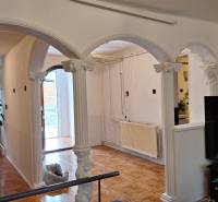 Családi ház belső tere íves oszlopokkal és fa dekorációjú padlóval.