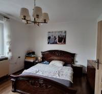 Hálószoba családi házban, ággyal, csillárral és fa dekorációjú padlóval.