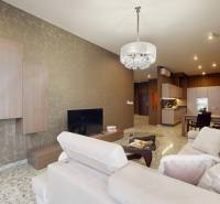 Nappali egy háromszobás lakásban bézs kanapéval és mintás tapétával.