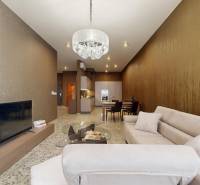 Nappali egy háromszobás lakásban kényelmes kanapéval, csillárral és televízióval.