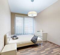 Hálószoba fa dekor padlóval és elegáns tapétával egy háromszobás lakásban.