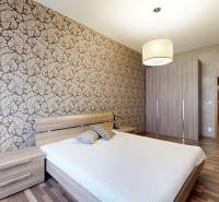 Hálószoba egy háromszobás lakásban mintás tapétával és fa dekorációjú padlóval.