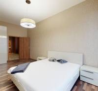 Hálószoba egy háromszobás lakásban, ággyal, szekrénnyel és fa dekorációjú padlóval.