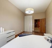 Hálószoba egy háromszobás lakásban, fa dekor padlóval és beépített szekrénnyel.