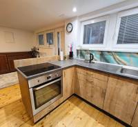 Konyha egy egyszobás lakásban mosogatóval, elektromos sütővel és fa dekorációjú padlóval.