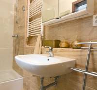 Fürdőszoba mosdóval, zuhanyzóval és tükrös szekrénnyel egy kétszobás lakásban.