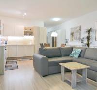 Nappali konyhasarokkal és fa dekorú padlóval egy kétszobás lakásban.