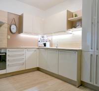 Konyha egy kétszobás lakásban fehér szekrényekkel és fa dekor padlóval.