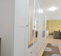 Folyosó fehér tükrös szekrénnyel és fa dekoros padlóval egy kétszobás lakásban.