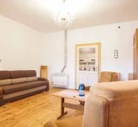 Nappali egy családi házban, fa dekorációjú padlóval, kanapéval és fotelekkel.