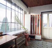 Családi ház belső tere virágcseréppel, asztallal és esernyőtartóval.