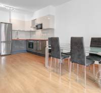 Konyha egy háromszobás lakásban fa dekor padlóval, kerámia asztallal és székekkel.