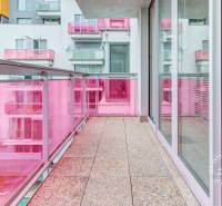 Erkély rózsaszín korláttal és üvegezett ajtókkal egy háromszobás lakásban.