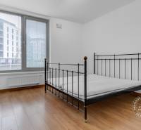 Hálószoba egy háromszobás lakásban fém ággyal és fa dekorációjú padlóval.