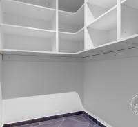 Gardrób egy háromszobás lakásban fehér polcokkal és kerámia padlóval.