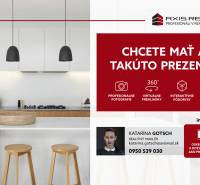 Konyha világos munkalappal, szigettel, két fa székkel és függő lámpákkal.