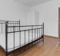 Háromszobás lakás hálószobája fém ággyal és fa dekorációjú padlóval.