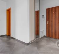 Folyosó sötét csempével, fa dekoros ajtókkal, összekötve a nappalival.