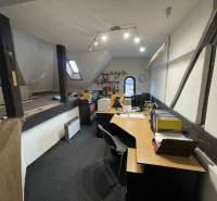 Iroda egy épületben, fa gerendákkal, íróasztalokkal és irodai kellékekkel felszerelve.