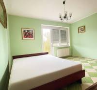 Hálószoba családi házban ággyal, pasztell falakkal és sakktáblaszerű padlóval.