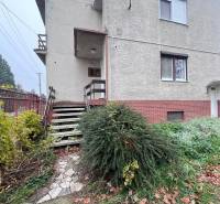 Családi ház Vághosszúfaluban téglából készült lábazattal, lépcsővel és rendezett kerttel.