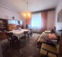 Családi ház belső tere étkezőasztallal, kanapéval és televízióval.