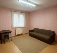 Szoba egy családi házban barna kanapéval, asztallal és fa dekorációjú padlóval.