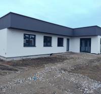 Lapos tetős, világos homlokzatú családi ház Zsigárdon.