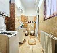 Fürdőszoba mosógéppel, mosdóval, WC-vel és világos kerámia csempével egy háromszobás lakásban.