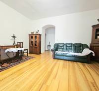 Nappali egy háromszobás lakásban, fa dekorációjú padlóval, kanapéval és fa bútorokkal.