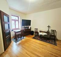 Szoba egy háromszobás lakásban, fa mintázatú padlóval és tévével az asztalon.