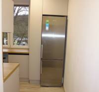 Konyha fa hatású padlóval és hűtőszekrénnyel egy kétszobás lakásban.