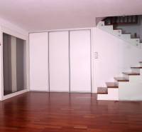 Családi ház belső tere fa dekorációjú padlóval és üvegkorlátos lépcsővel.